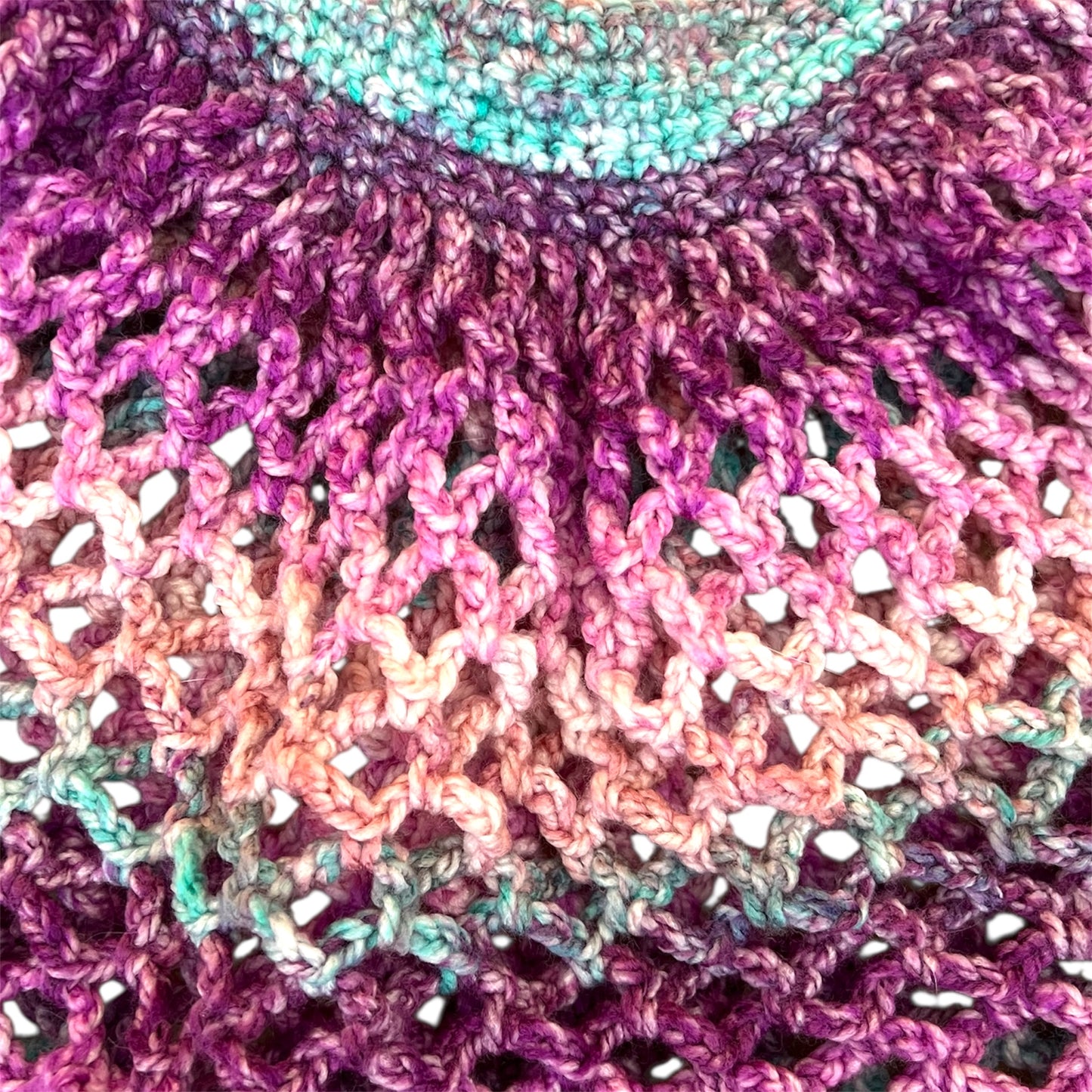 Close up picture of a pink and purple handmade crochet mesh market bag