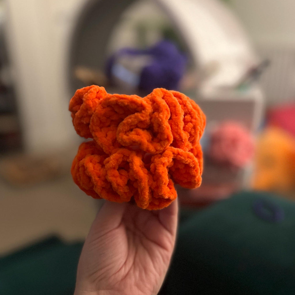 Person holding 2 handmade crochet orange sheffield steelers themed coloured scrunchies
