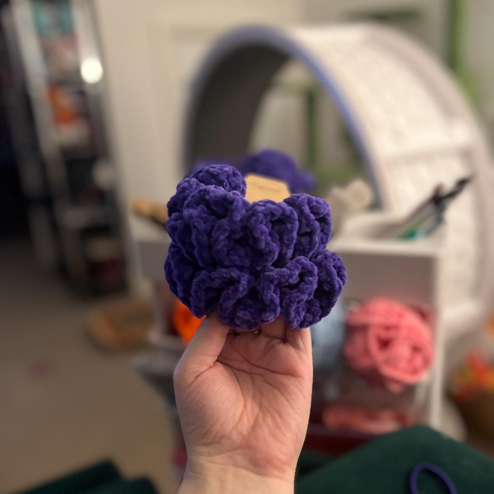 Person holding 2 handmade crochet purple manchester storm themed coloured scrunchies