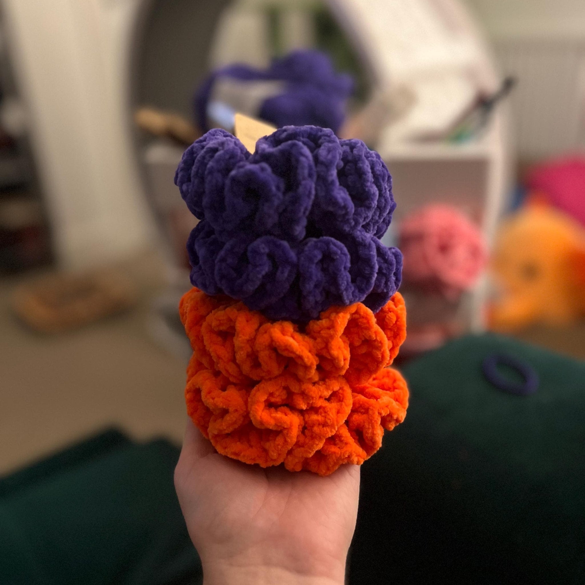 Hand holding 2 purple manchester storm purple scrunchies and 2 orange sheffield steelers scrunchies
