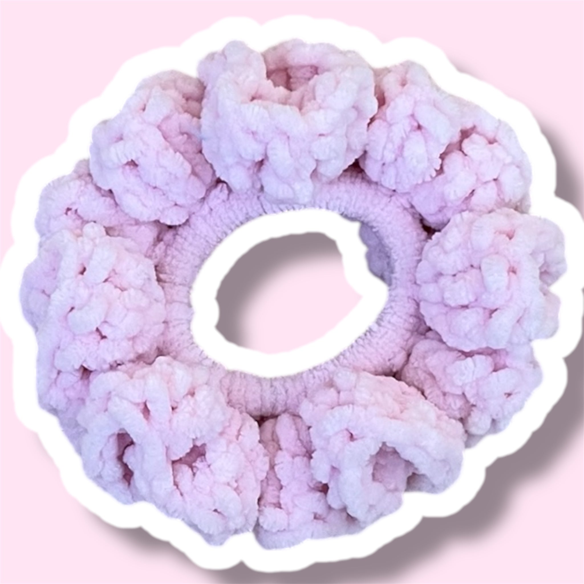 Close up image of a baby pink handmade crochet scrunchie on a light pink background