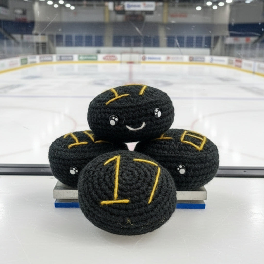 Four black crochet plush ice hockey plush with gold nottingham panthers themed colour accents in front of an ice rink