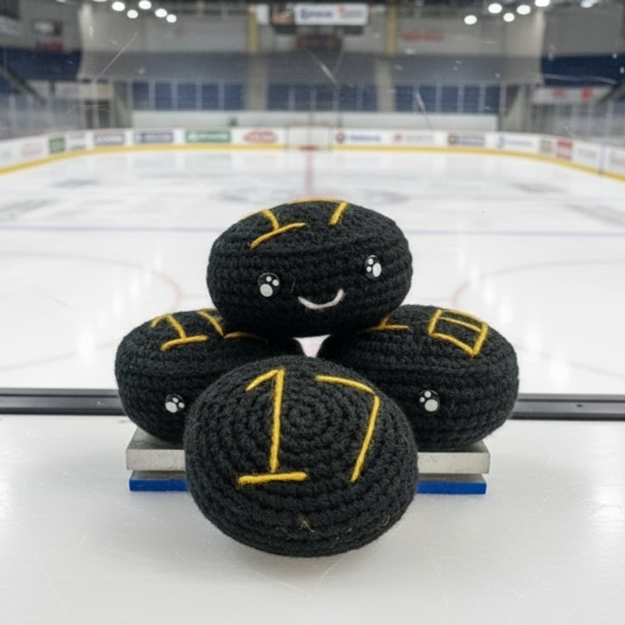 Four black crochet plush ice hockey plush with gold nottingham panthers themed colour accents in front of an ice rink