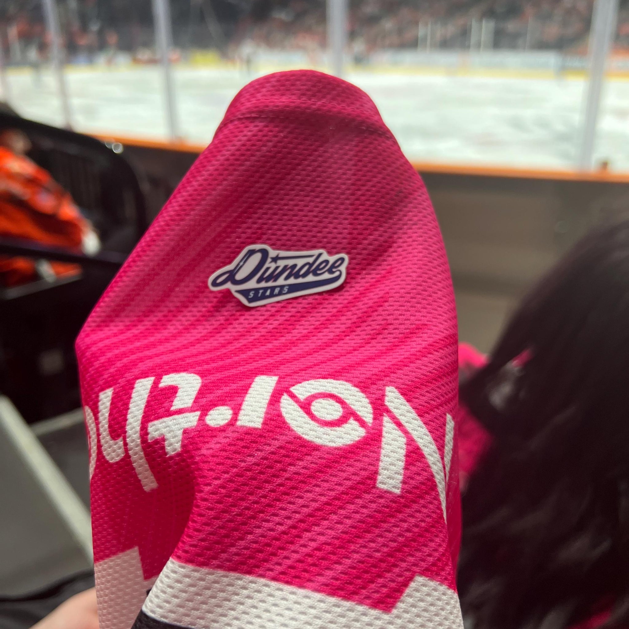 Holding a physical sticker of dundee stars ice hockey team logo at an ice hockey game