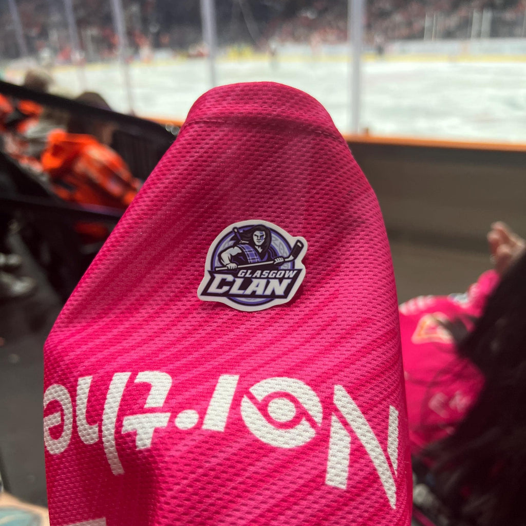 Holding a physical sticker of glasgow clan ice hockey team logo at an ice hockey game