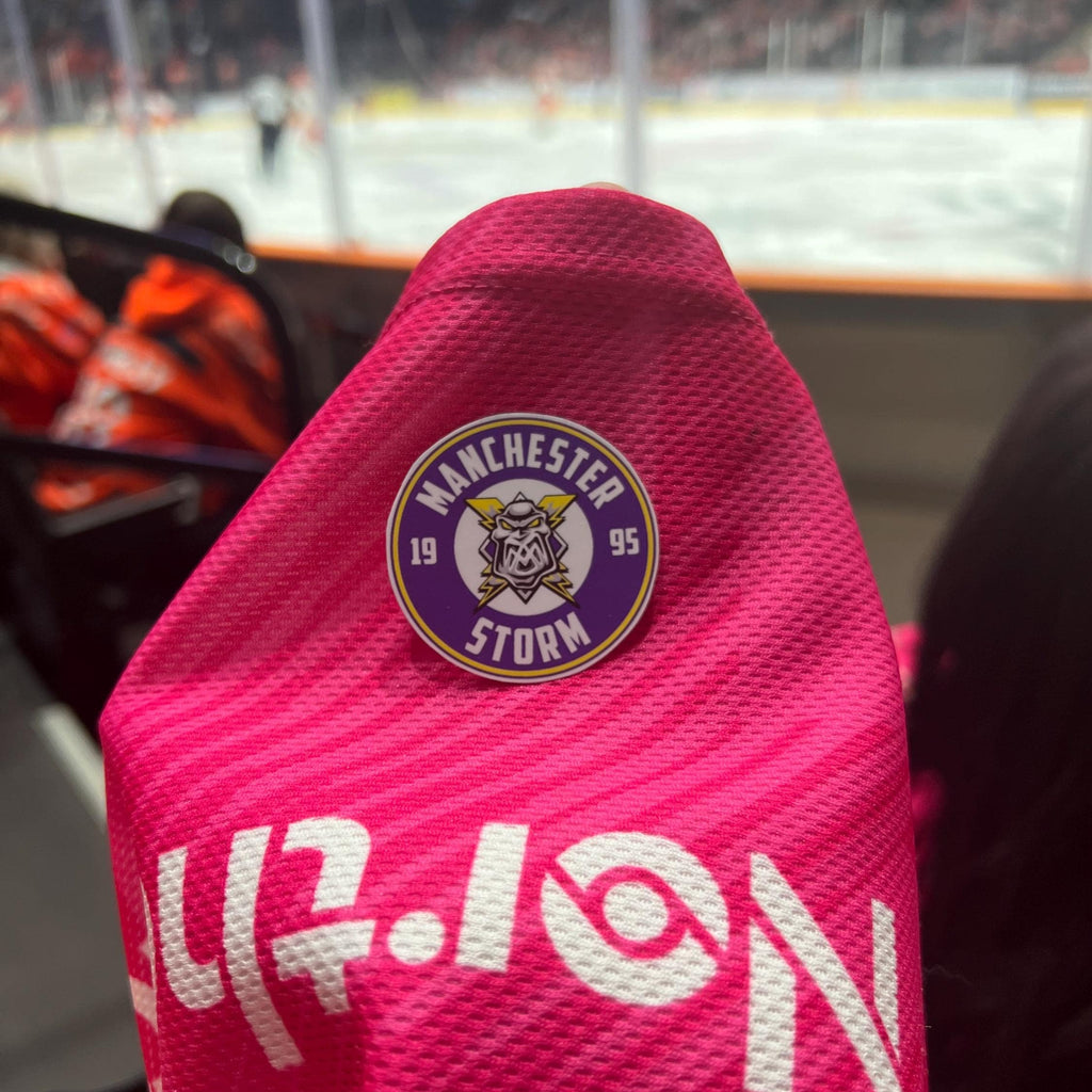 Holding a physical sticker of manchester storm ice hockey team logo at an ice hockey game