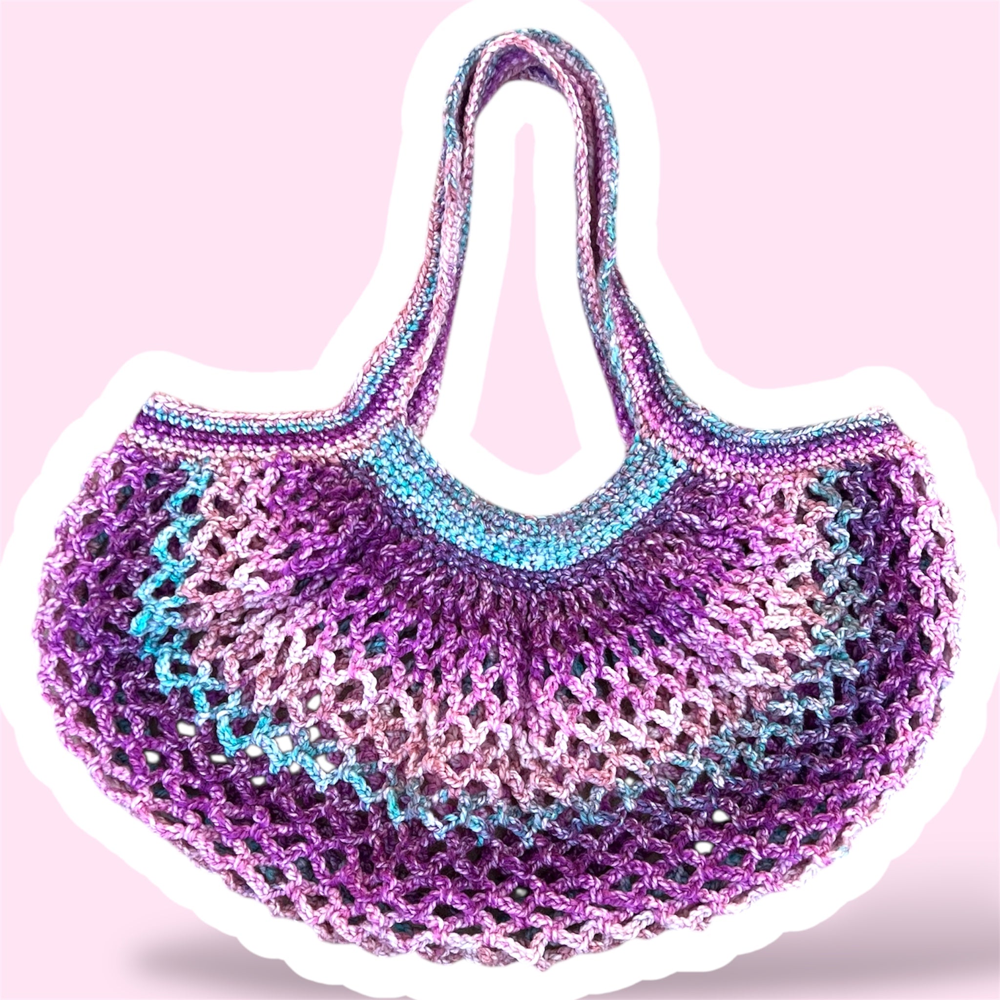 A picture of a purple and pink handmade crochet mesh market bag on a plain light pink background