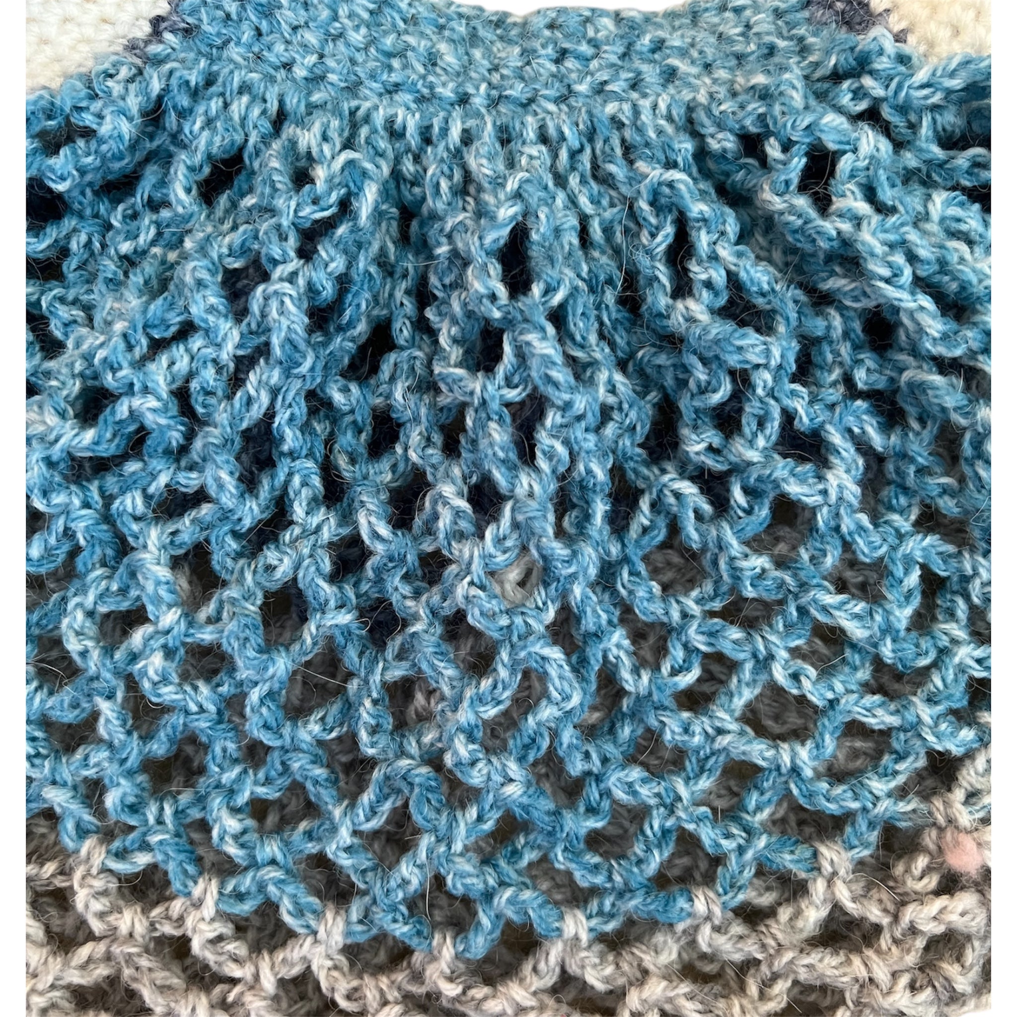 Close up of a crochet mesh market bag with blue and grey gradient colours
