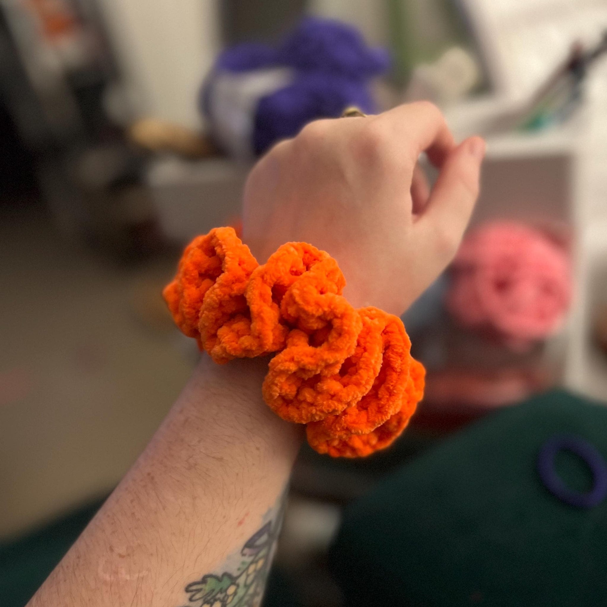 Handmade crochet scrunchie around a wrist that is orange sheffield steelers themed colour