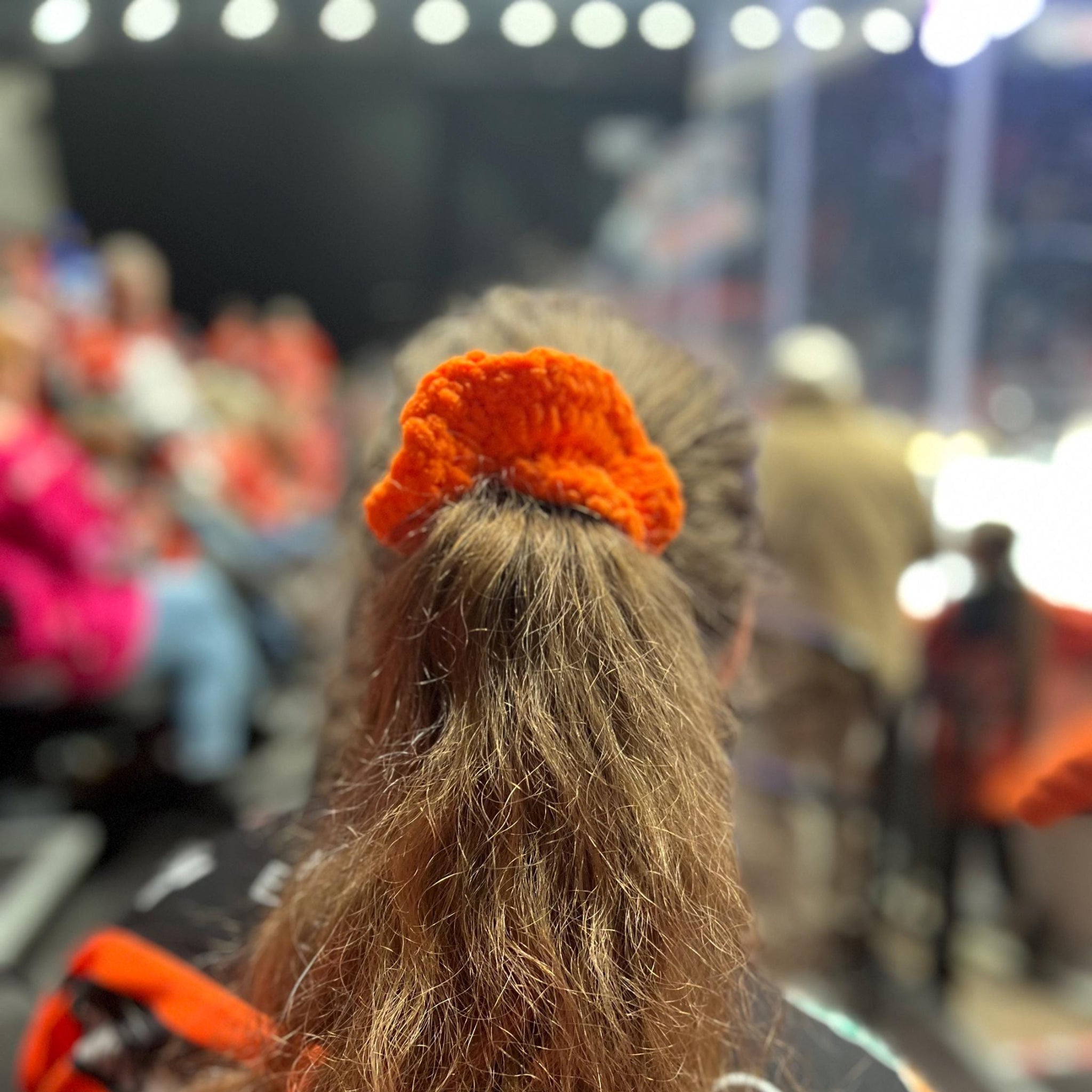 Person with long hair wearing an orange sheffield steelers themed colour scrunchie