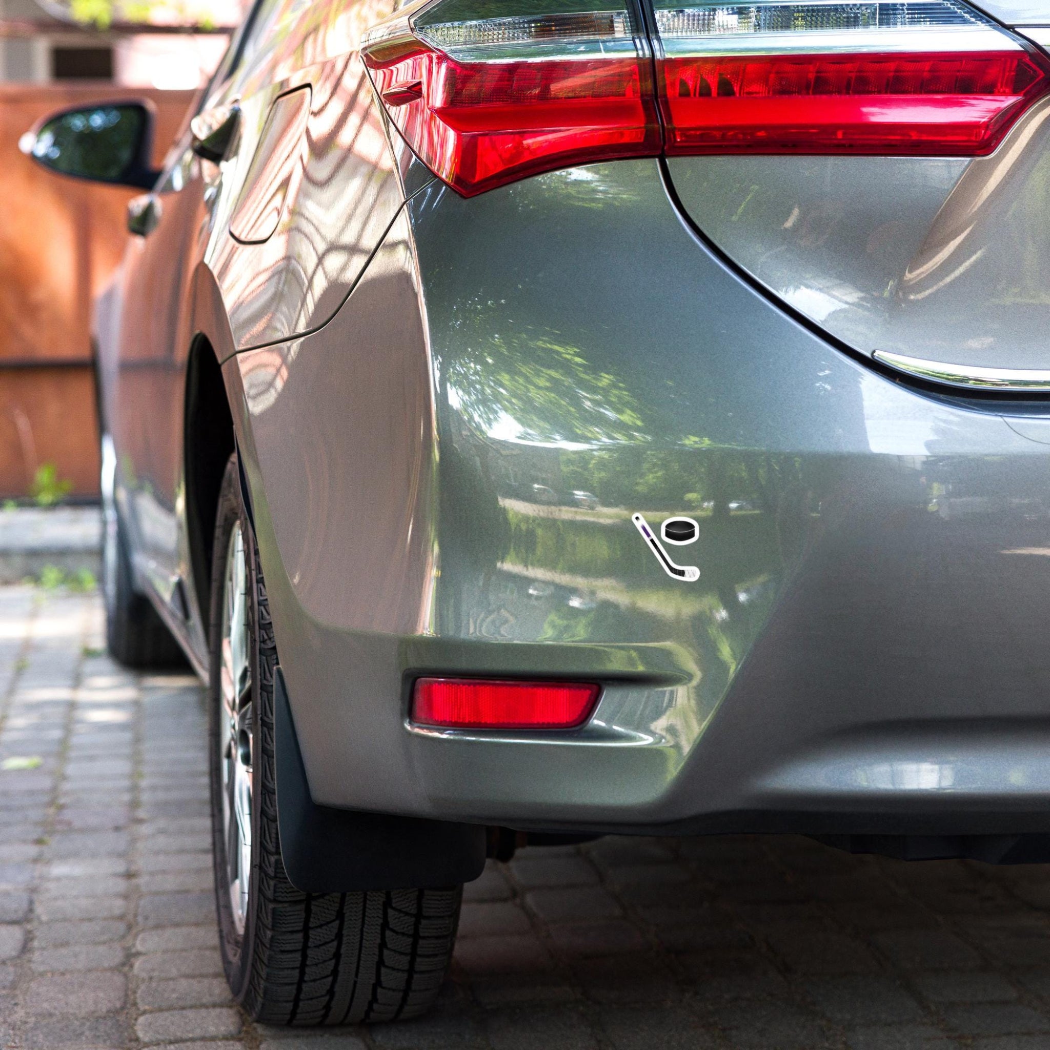 Close up of the back of a car showing an ice hockey stick sticker and ice hockey puck sticker
