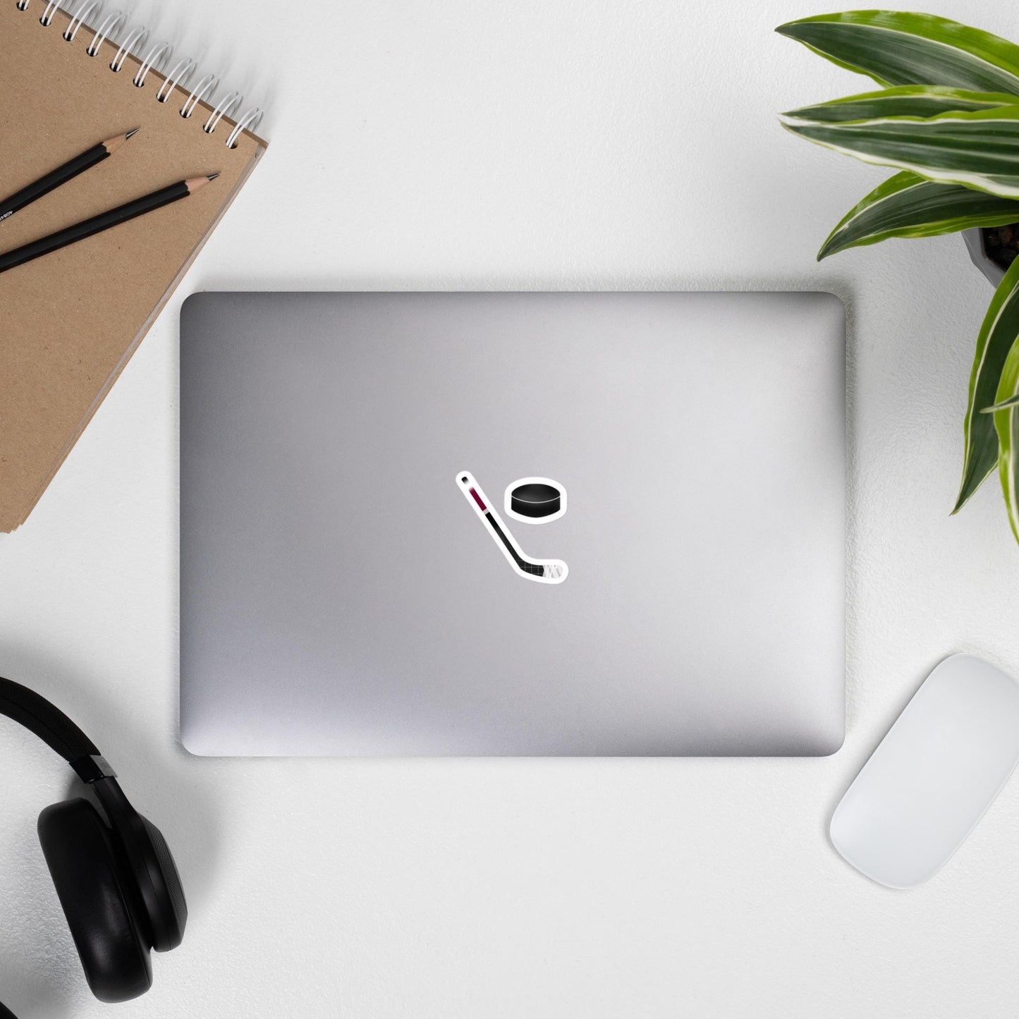 Laptop on a desk with an ice hockey stick sticker and ice hockey puck sticker